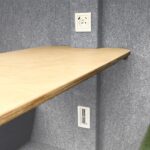 Blat i gniazda elektryczne wewnątrz szarej kabiny akustycznej
